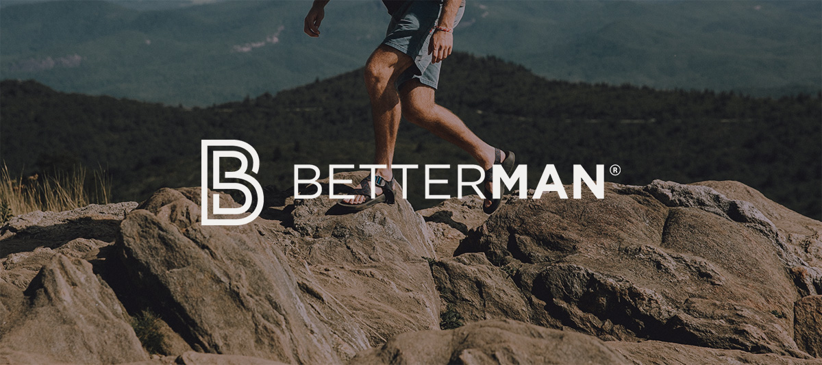 man covering rough terrain with hiking sandals and the words BETTER MAN in the middle in white